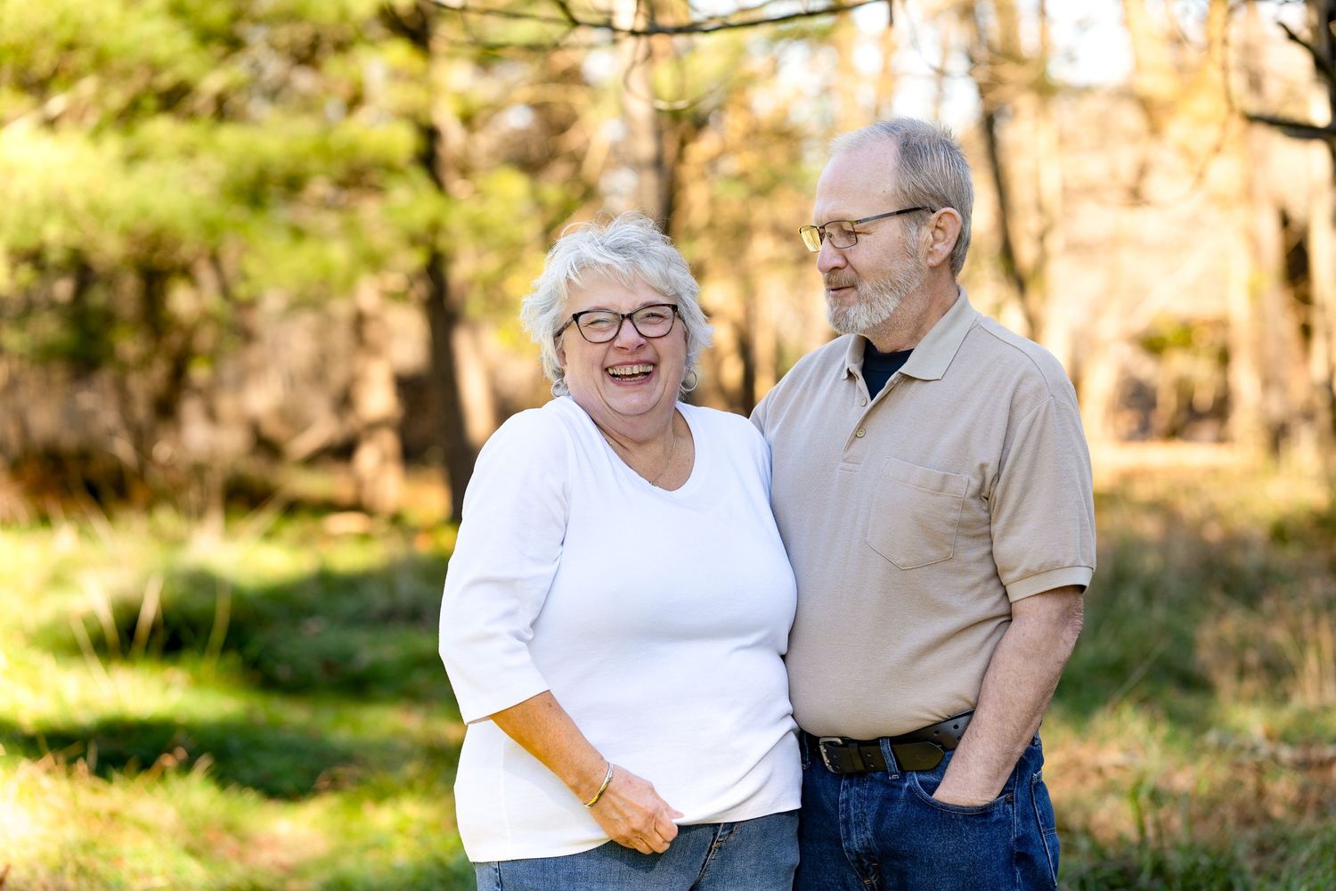 Elderly couple sharing a joyful moment outdoors in natural sunlight.