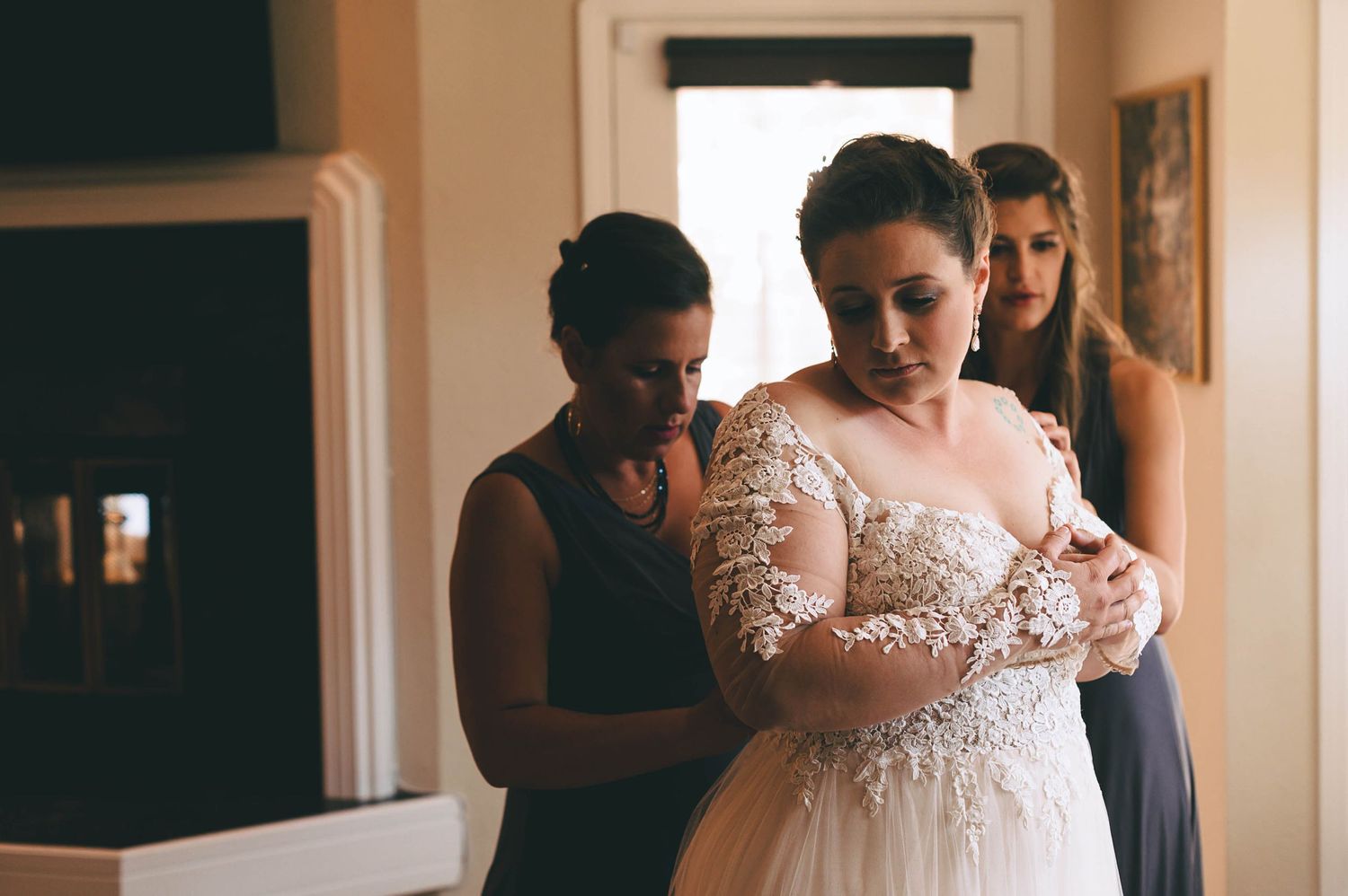 Plus size bride getting into her beautiful lace dress.