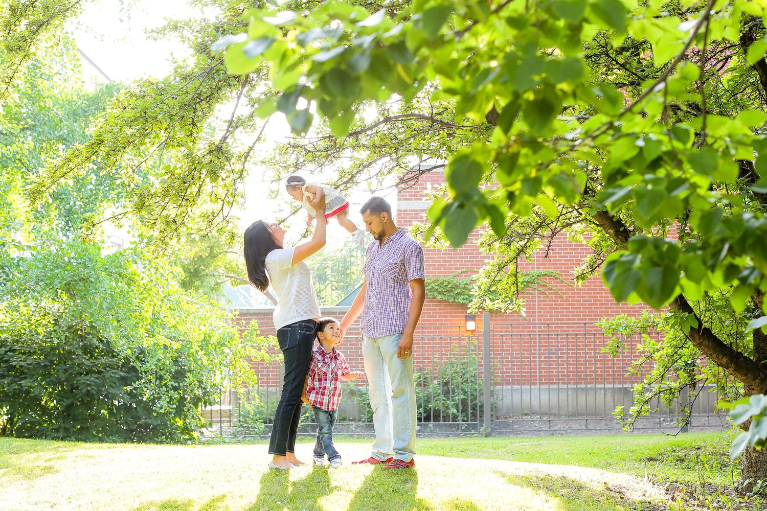 Family walking together through a lush green garden path on a sunny day.