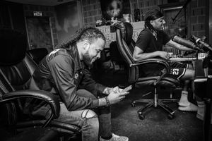 Black and white photo of recording studio session with multiple people at workstations.