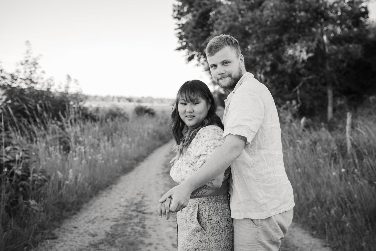 Black and white portrait of a couple embracing on a rural pathway.