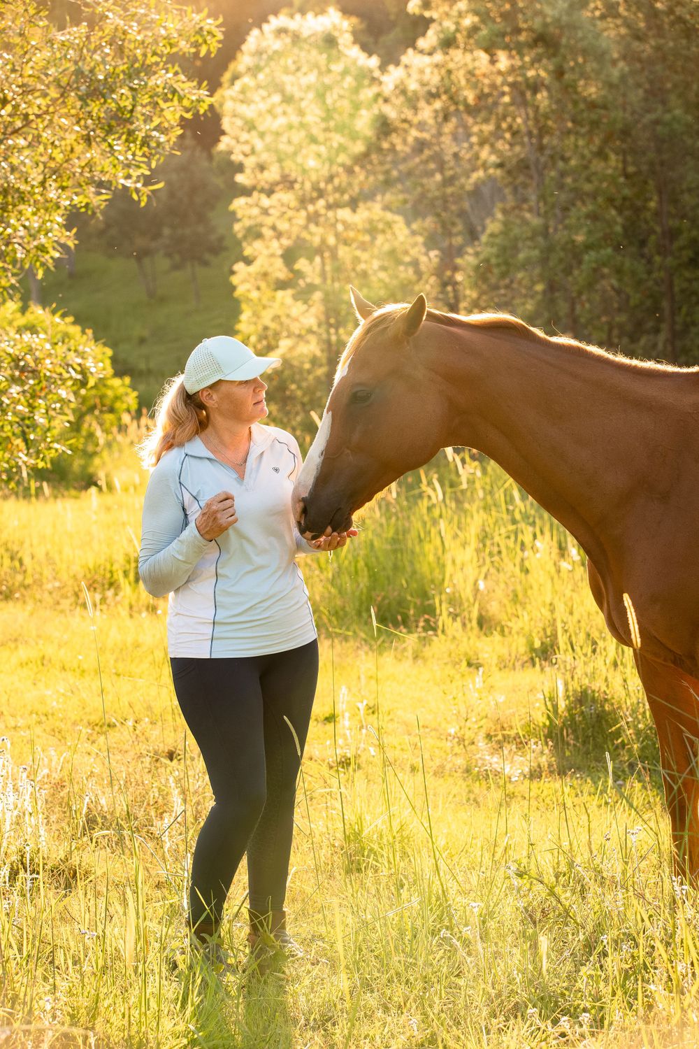 woman with horse in field at sunset