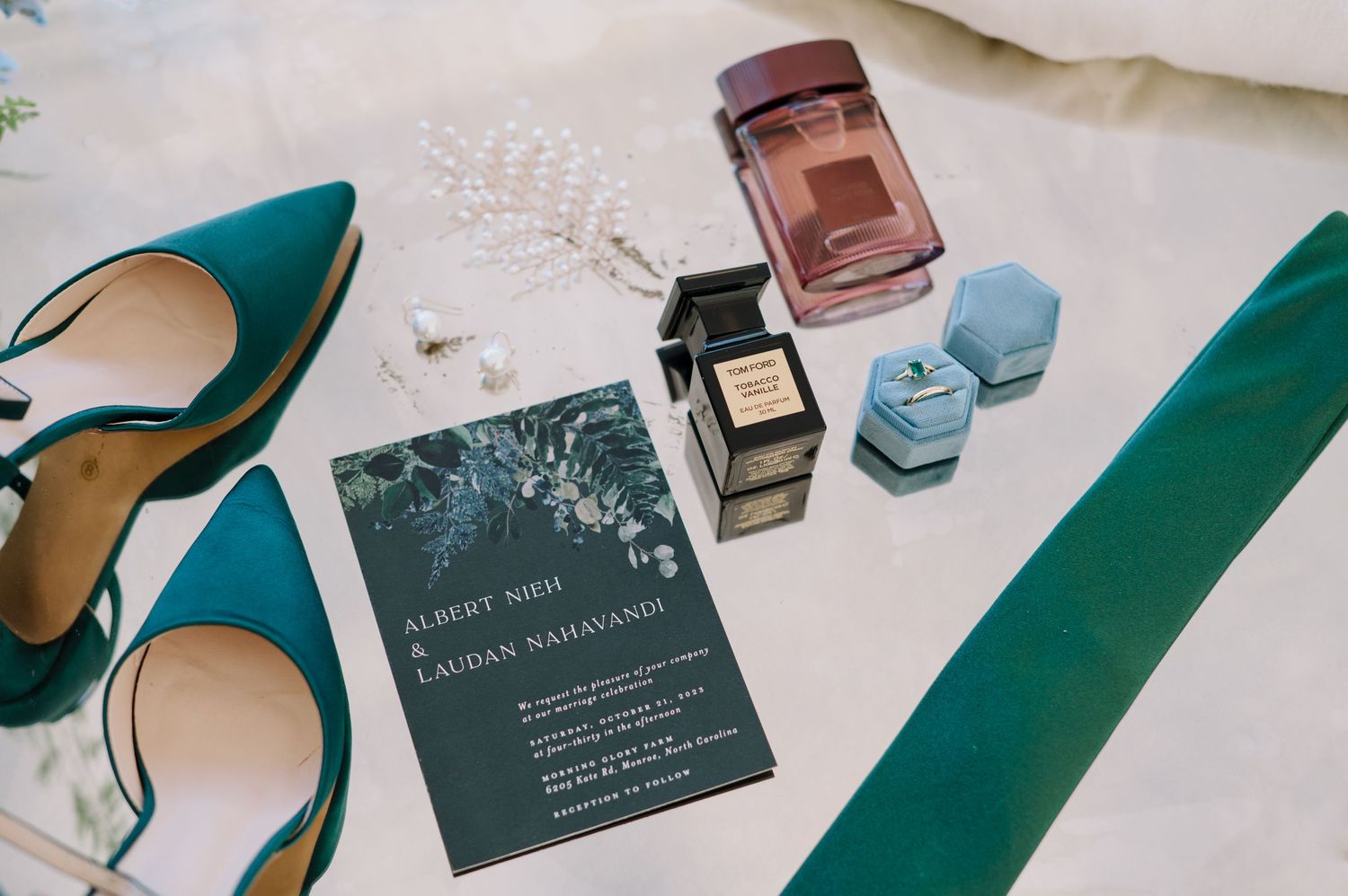 wedding details in shades of green and blue on a mirror table