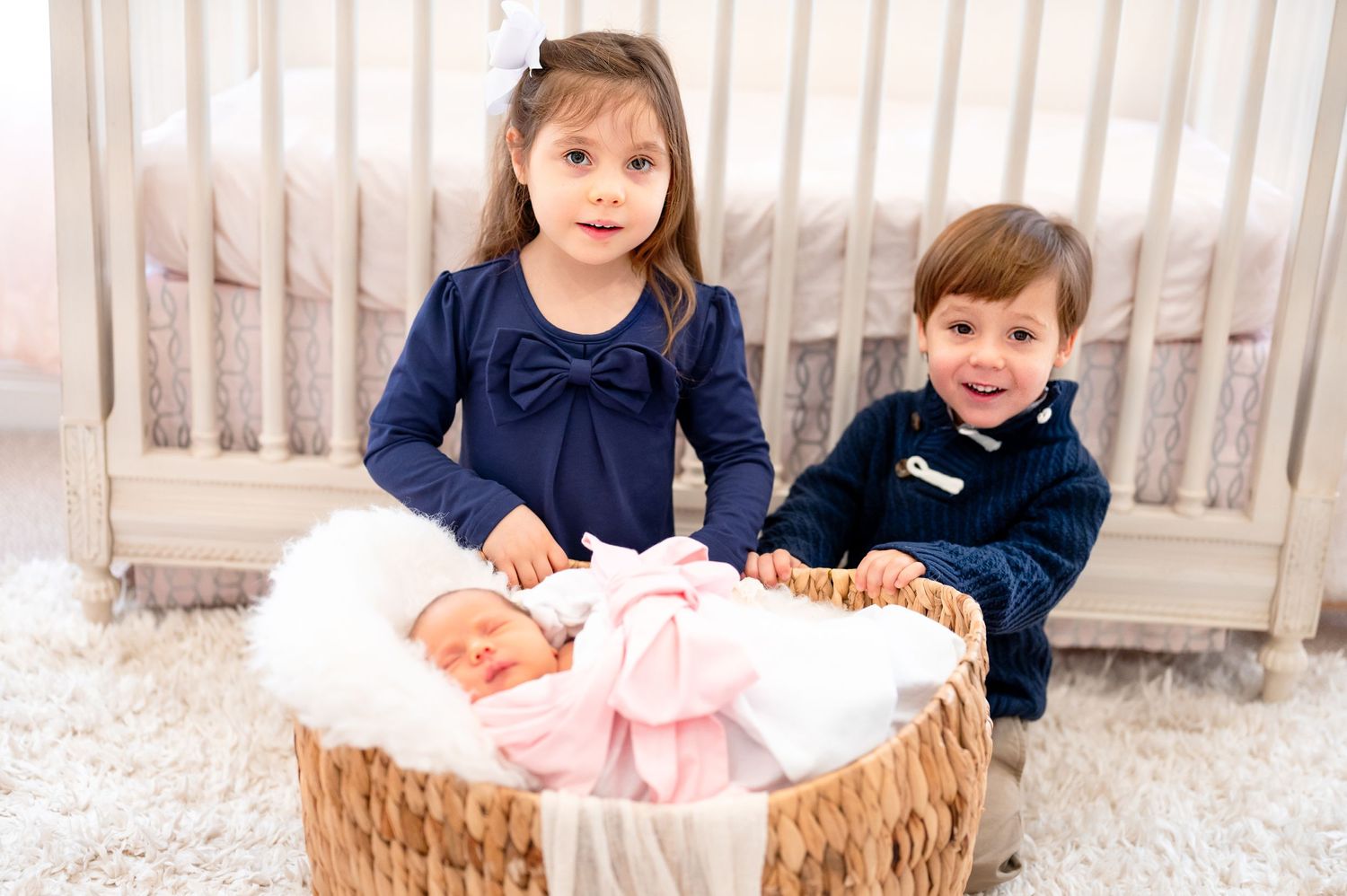 brother and sister smiling for a portrait for a in home newborn baby girl lifestyle session inside the girl nursery