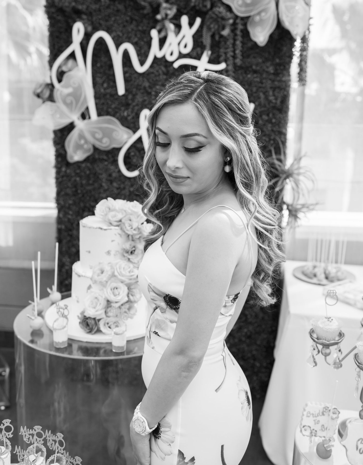 Black and white photo of bride with elegant cake at bridal shower.