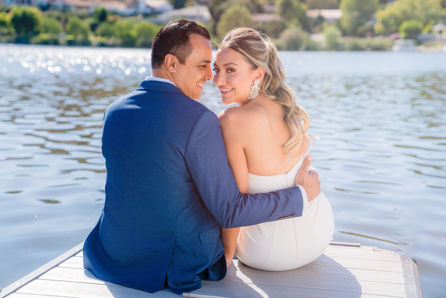 Romantic couple sitting together on a boat overlooking a serene lake on their wedding day.