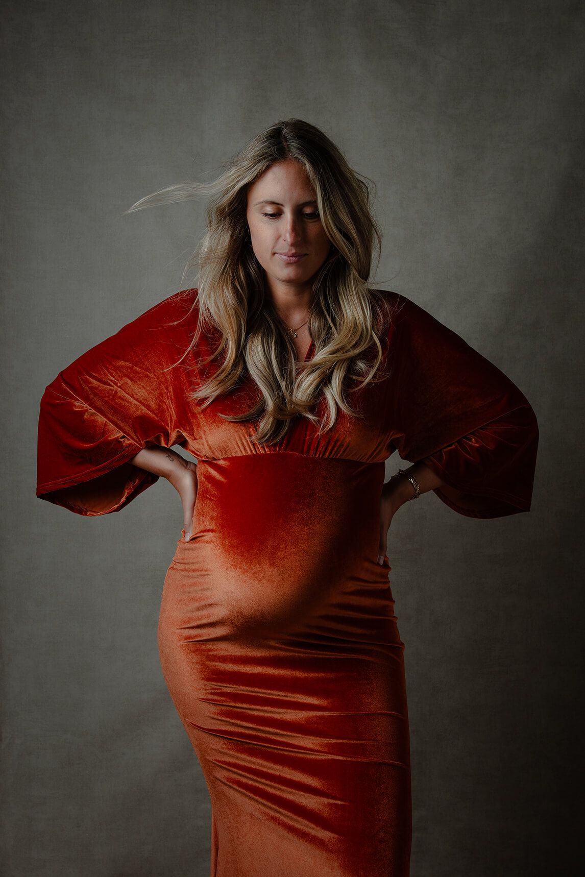Zwangerschapsshoot studio -  vrouw in lange oranje jurk