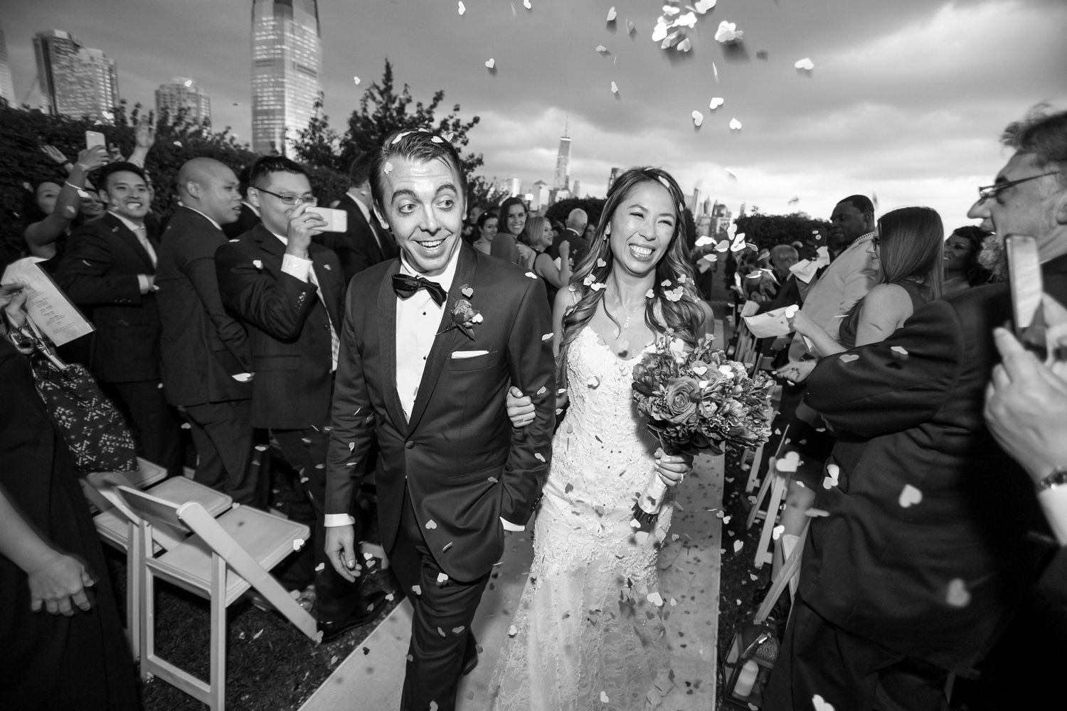 Newlyweds celebrate with joy as confetti falls around them at their outdoor wedding.