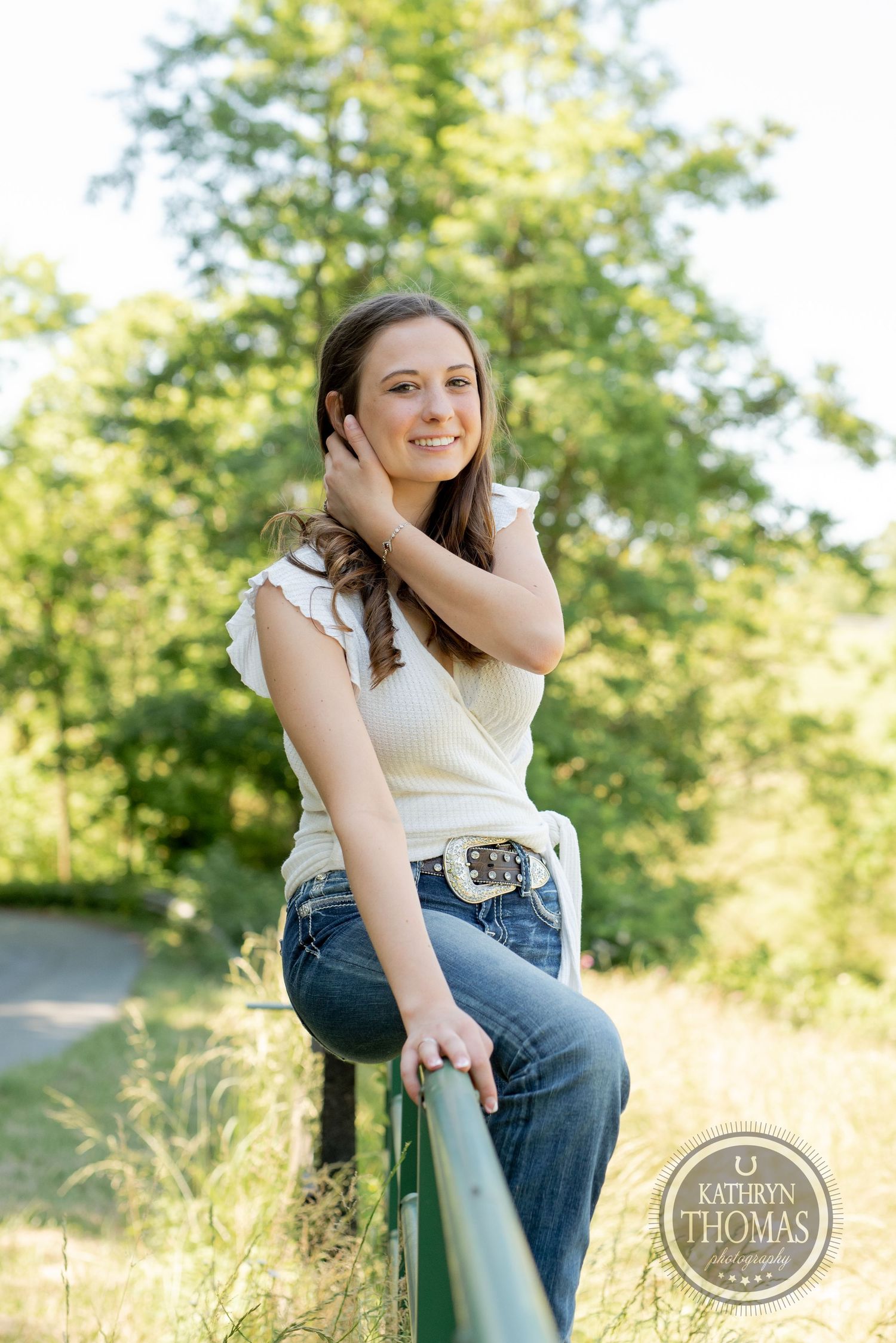 A relaxed outdoor portrait on a green railing surrounded by golden grass.