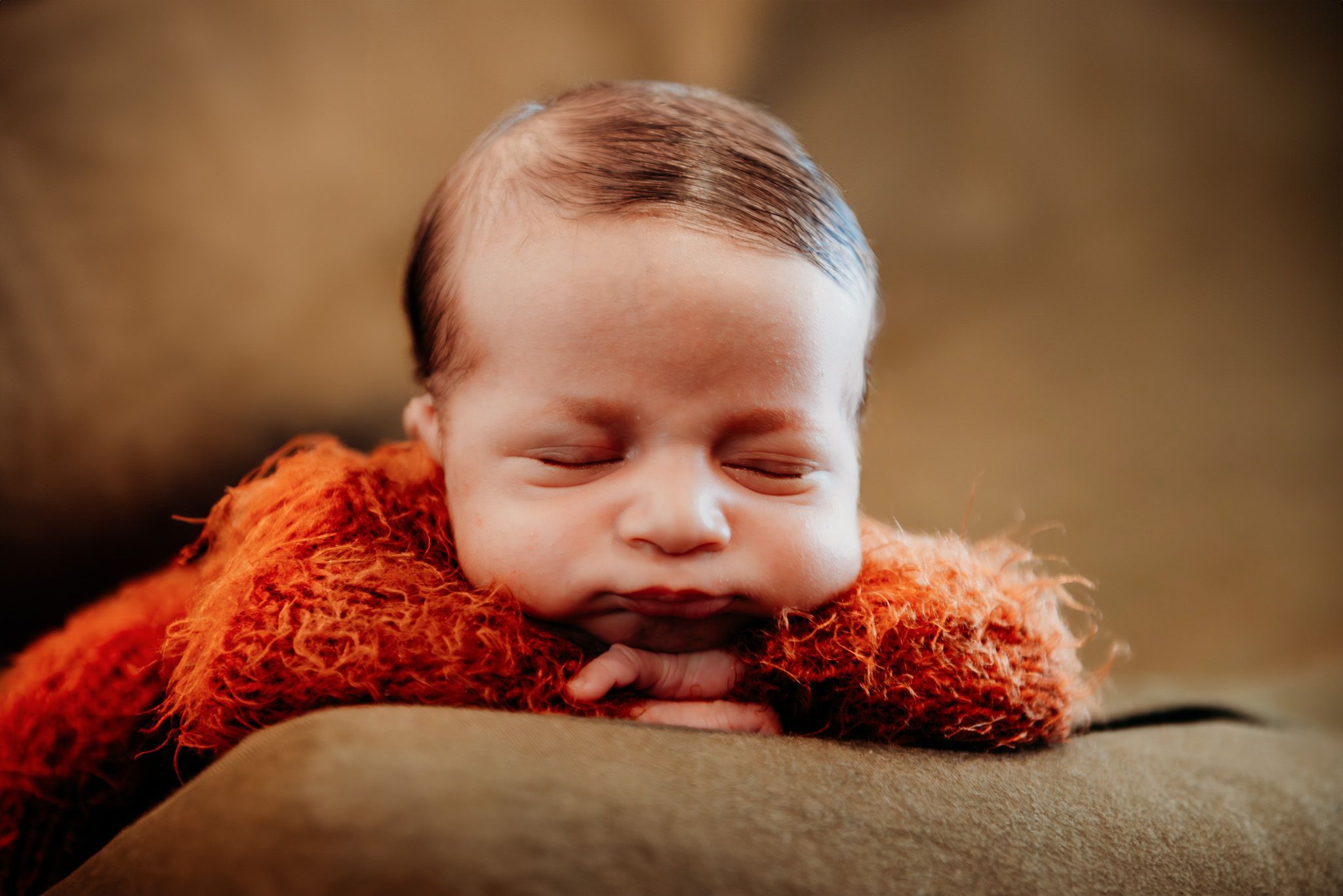 Sleeping baby nestled in cozy orange textured fabric.