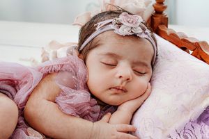 Dreamy newborn photography in soft pink tones with delicate lace details.