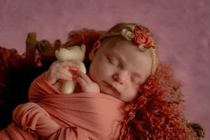 Soft and dreamy newborn photography in muted pink tones.