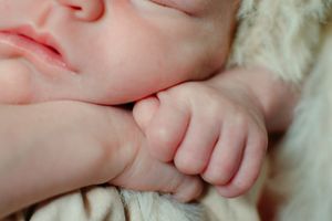Close-up details of delicate pink baby hands and fingers against a soft background.
