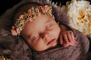 Peaceful newborn photography setup with soft floral decorations and delicate wrapping.