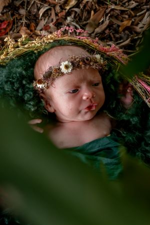 Artistic newborn photography with a floral crown and dark moody lighting.