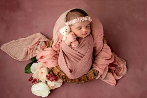 Soft pink newborn photography setup with delicate floral accents.