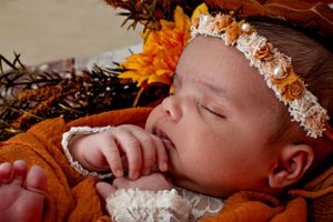 Autumn-themed newborn portrait with sunflowers and white lace details.