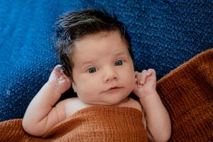 Artistic portrait against deep blue textured background with brown fabric accent.