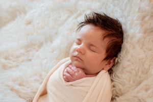 Peaceful sleeping pose on soft cream textured blanket.