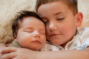 Two children resting peacefully together on soft bedding in an intimate portrait.