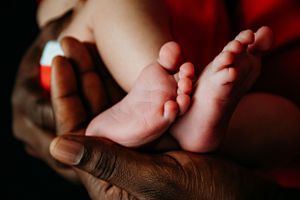 Close-up detail shots of newborn baby feet and hands with dramatic lighting.