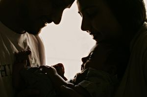Silhouetted figures in intimate moment against bright backlight.