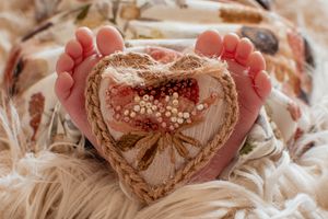 Tiny baby feet forming heart shape with lace and floral decorations.