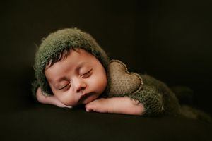 Sleeping baby wearing knit hat in dark moody portrait style.