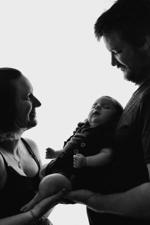 Black and white portrait of a family sharing an intimate moment with their baby.