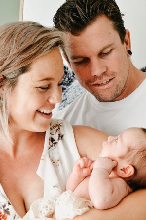 Intimate family moment with newborn baby against white background.