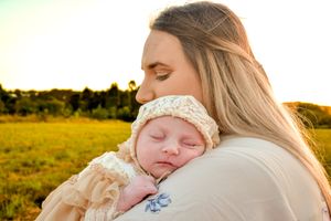 A tender moment captured during sunset in a grassy field with warm golden light.