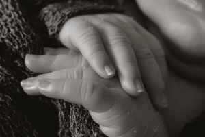 Black and white close-up of small hands gently touching each other.