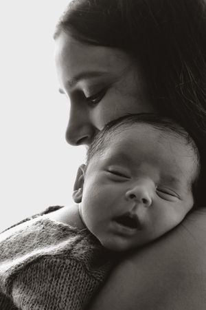 Black and white intimate portrait of infant sleeping against shoulder.