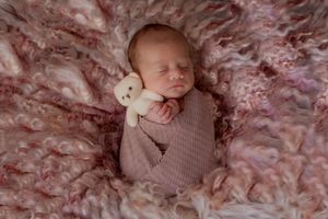 Soft pink fluffy textured fabric creates a dreamy backdrop for newborn photography.