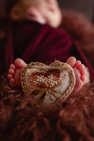 Tiny feet resting on textured brown fabric with delicate white decorative details.