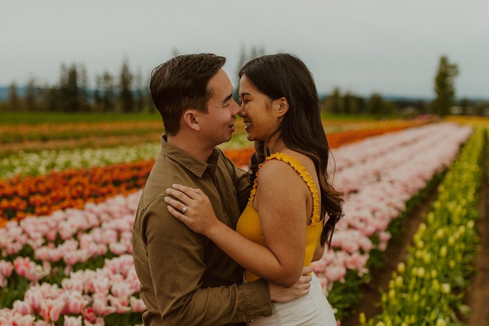 A loving couple shares an intimate moment among rows of blooming tulips.