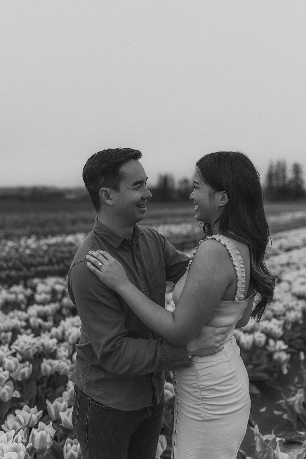 A tender black and white portrait of a couple embracing in a flower field.