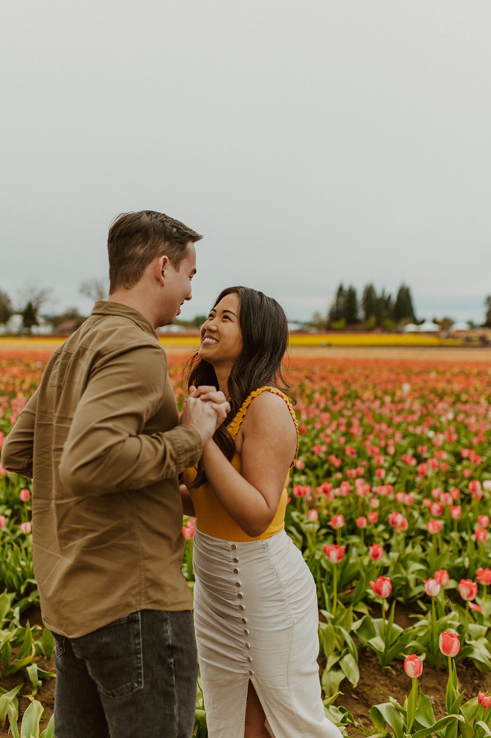 A romantic couple shares a tender moment in a vibrant tulip field during golden hour.