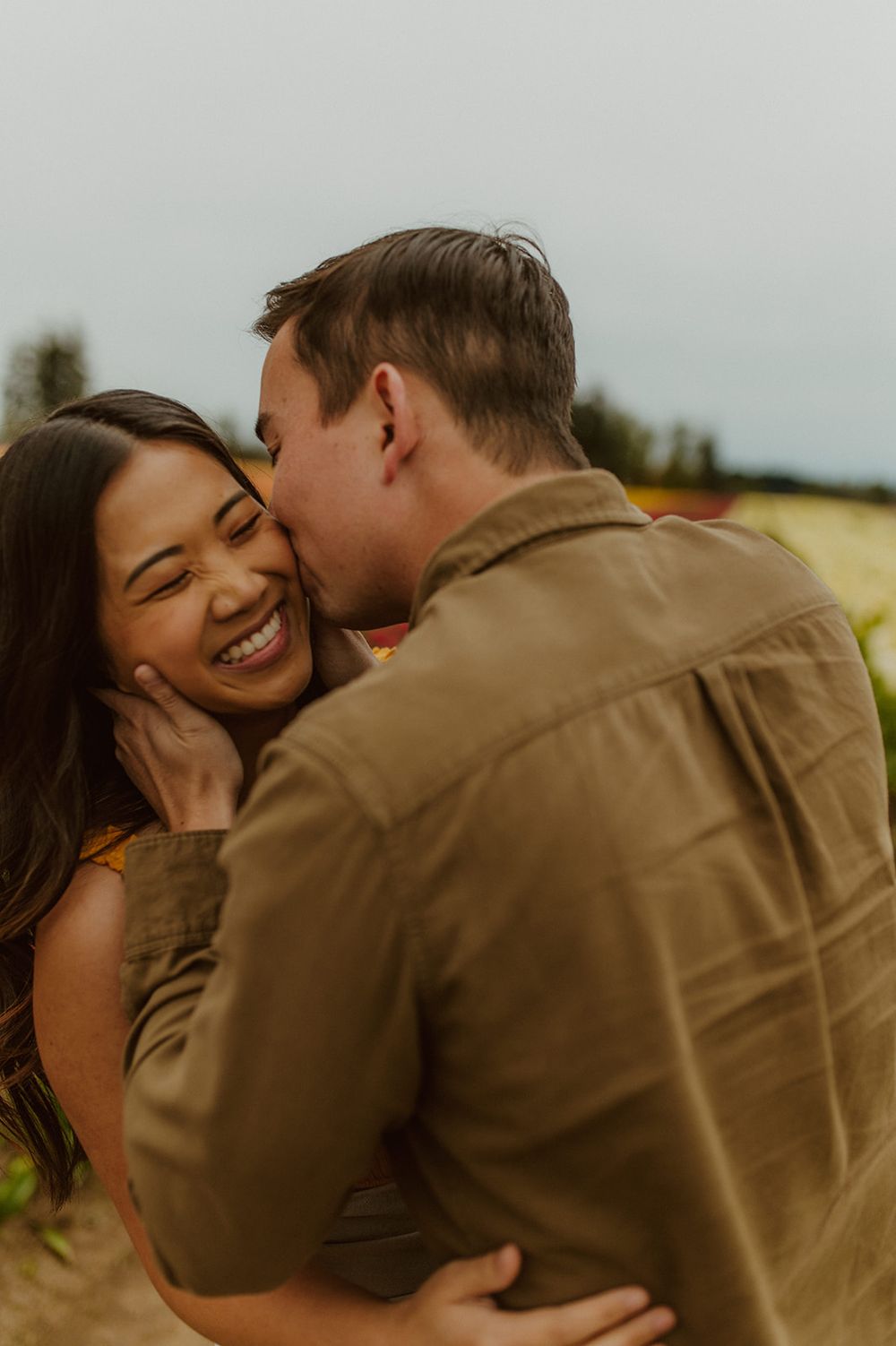 A joyful embrace shared between a couple in a blooming flower field at sunset.