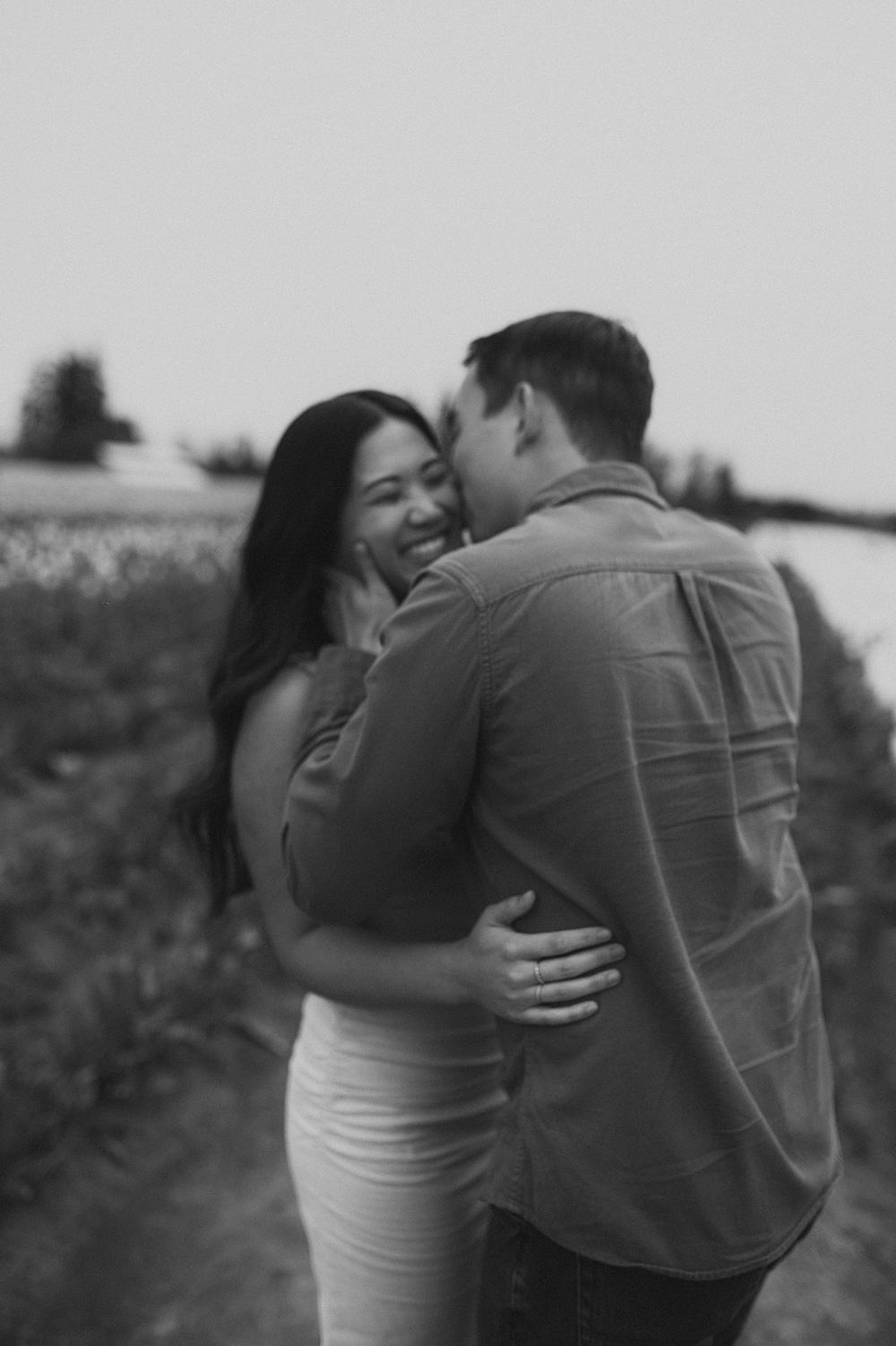 Black and white photo of a couple sharing an intimate moment in a flower field.