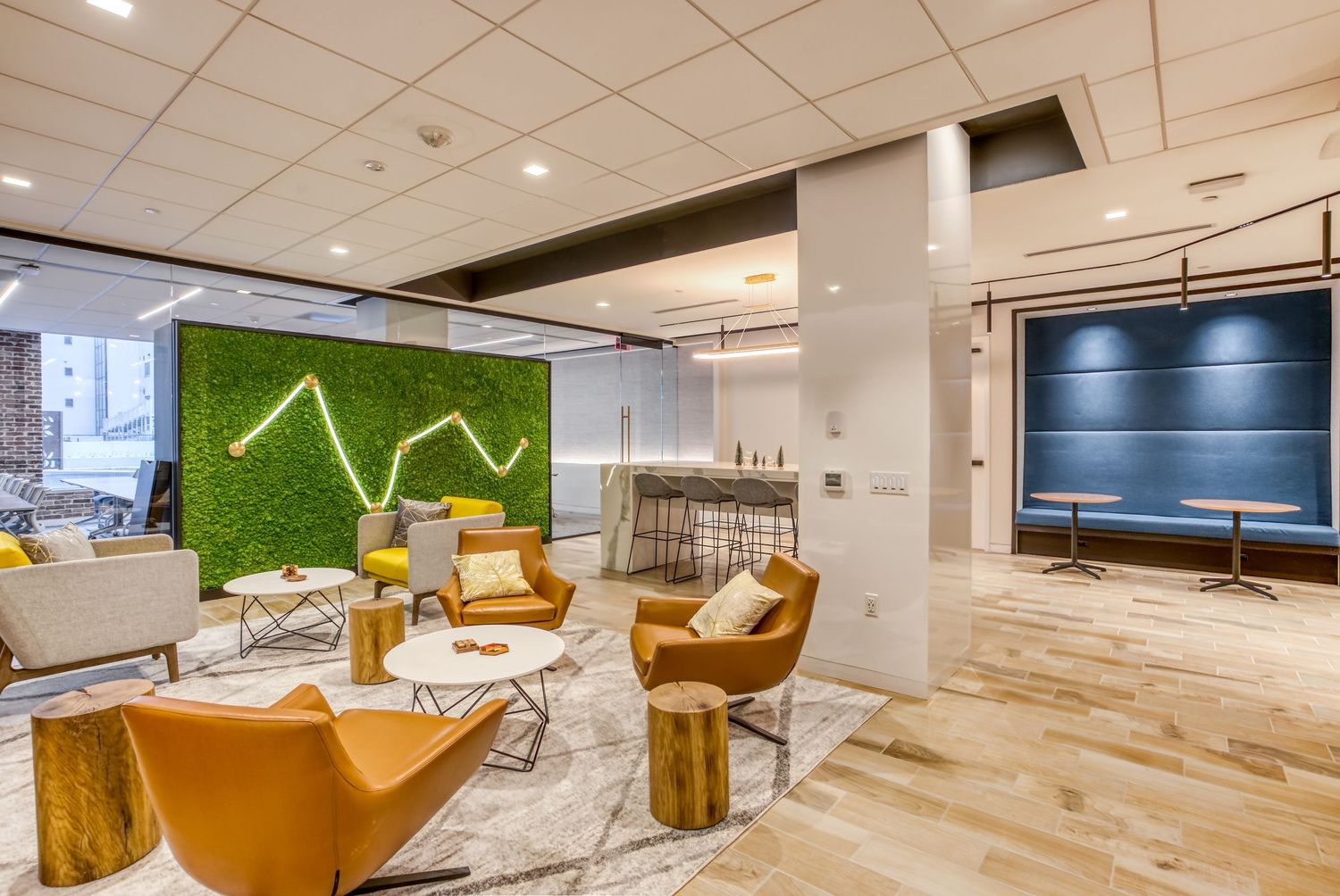 Modern office lounge with yellow chairs and green living wall feature.