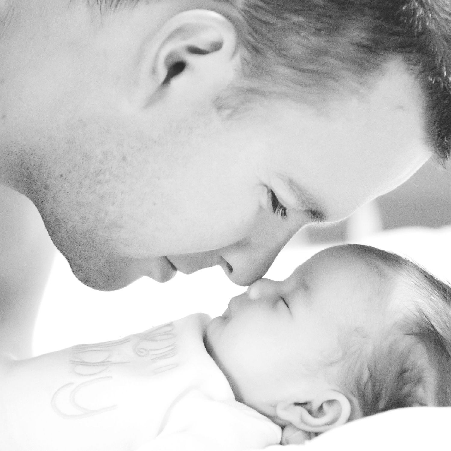 Intimate black and white portrait of tender moment between parent and newborn baby.