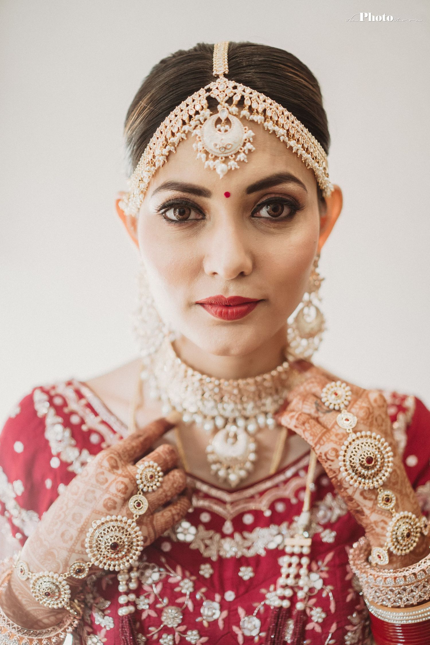 Traditional Indian bridal jewelry and makeup with pearl mathapatti and red embroidered outfit.