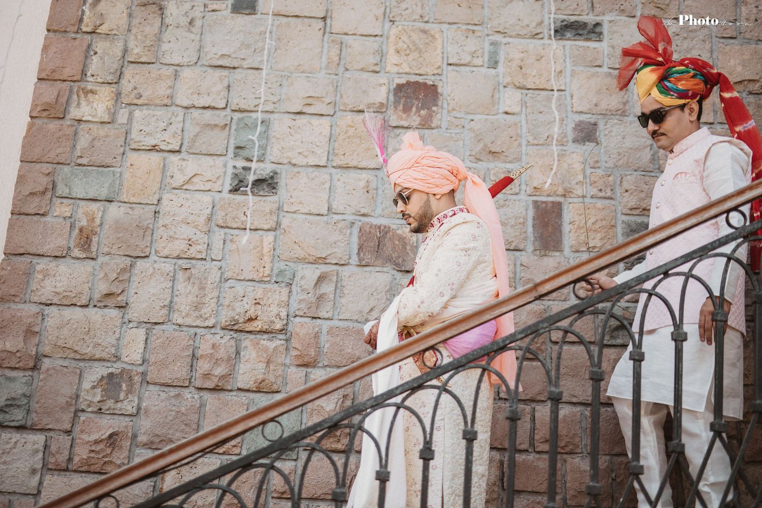 Wedding party members gathered on stone staircase in traditional Indian formal wear.