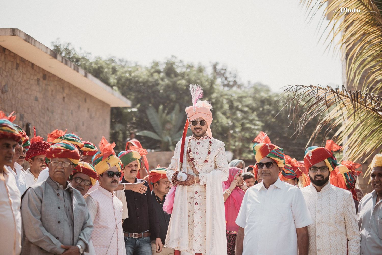 Festive wedding procession with guests wearing orange turbans and traditional Indian clothing.
