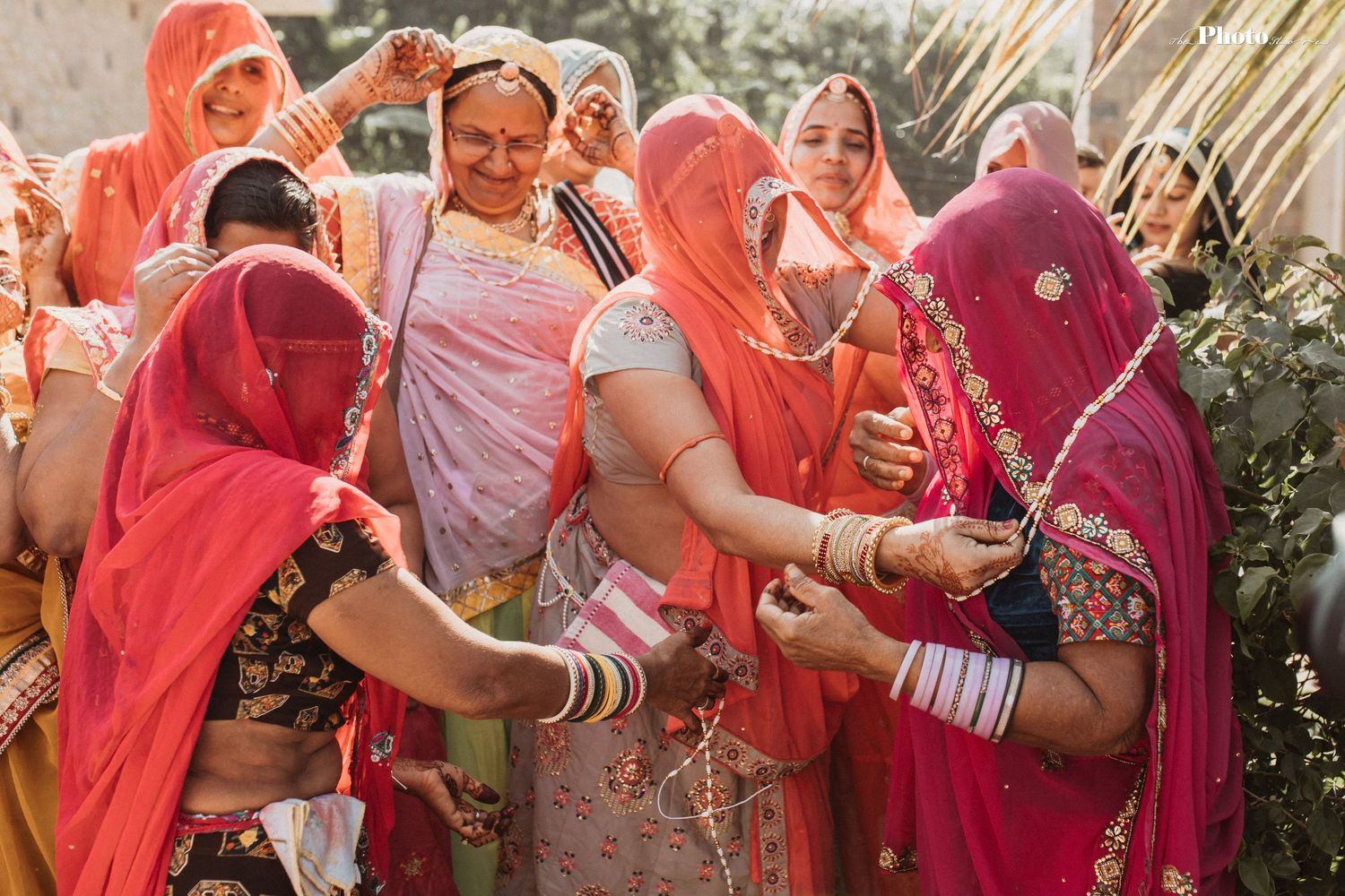 Women in colorful saris and traditional jewelry celebrate during an Indian wedding ceremony.