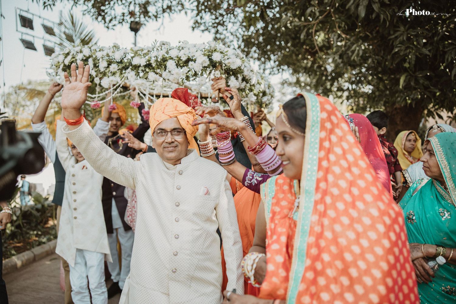Outdoor celebration with colorful umbrellas and traditional decorations under trees.