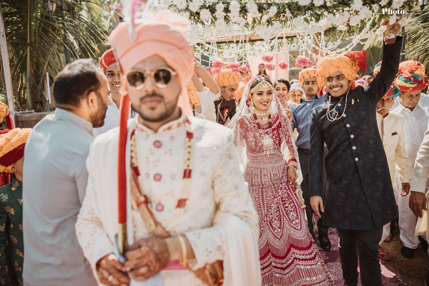 Traditional wedding celebration with guests in formal attire under floral decorations.
