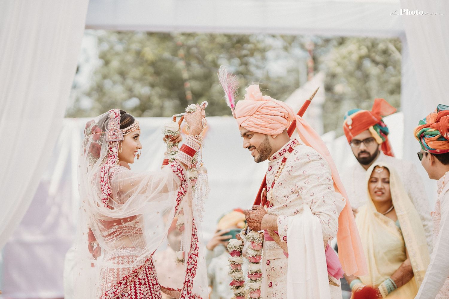 Traditional Indian wedding ritual taking place under white tent with decorative elements.