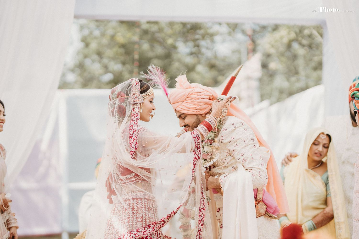 Intimate moment during an Indian wedding ceremony with pink and white decor elements.